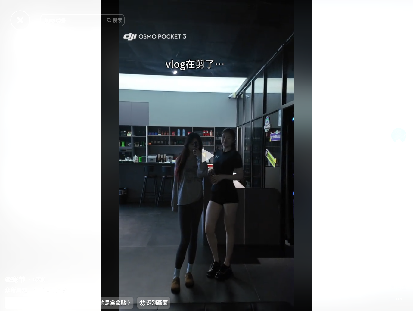 Two women standing in a dimly lit room, one holdin